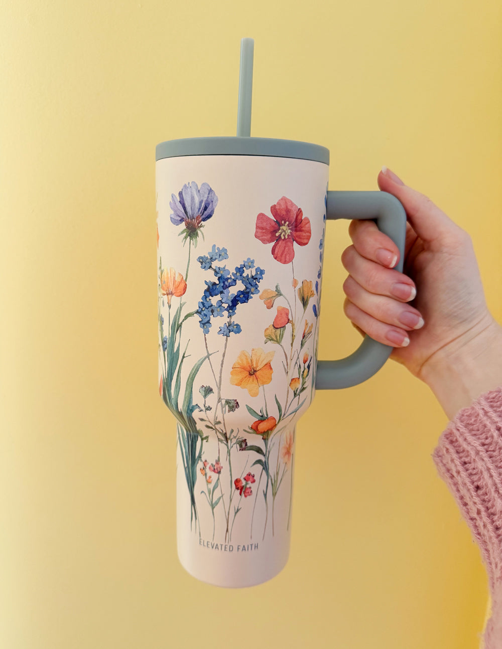 Floral 40 oz tumbler with gray handle and straw lid, held up