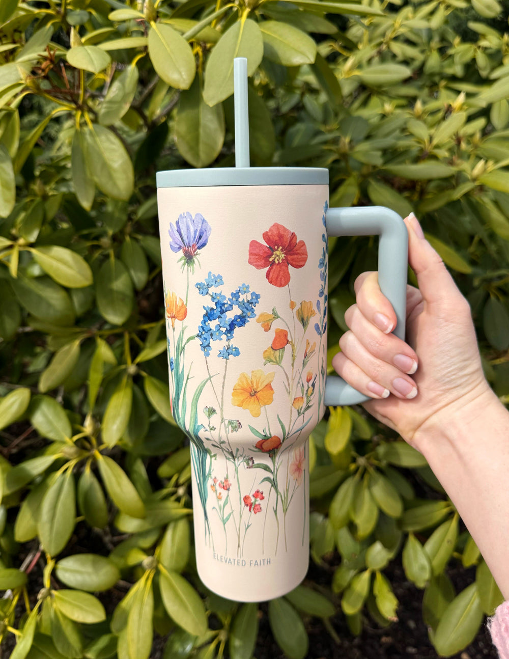 Floral 40 oz tumbler with gray handle and straw lid, close-up hand grip