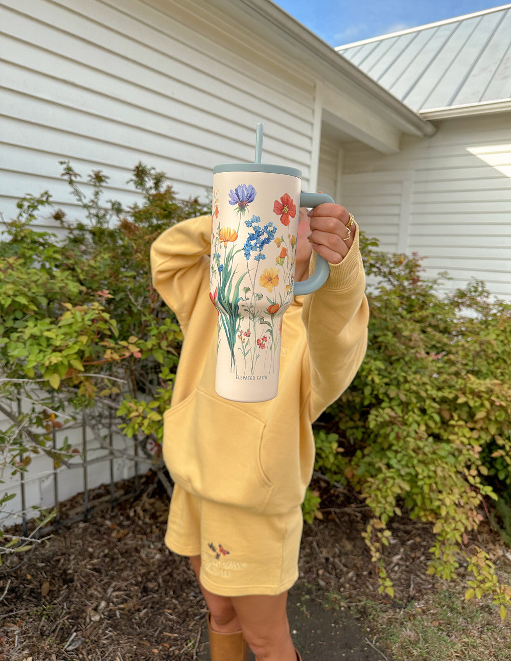 Floral 40 oz tumbler with gray handle and straw lid, held in hand