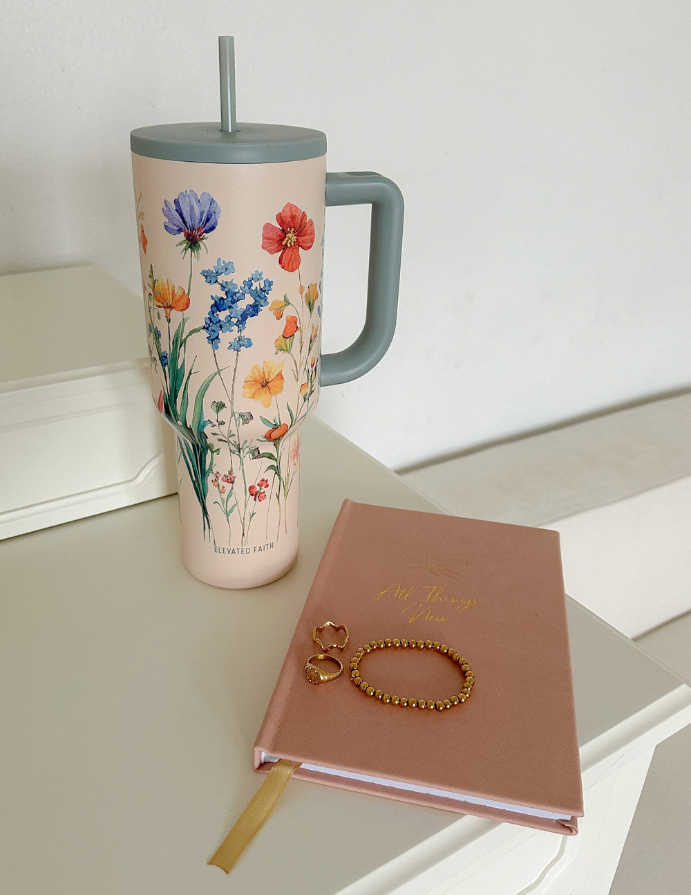 Floral 40 oz insulated tumbler with gray handle and straw lid, standing view