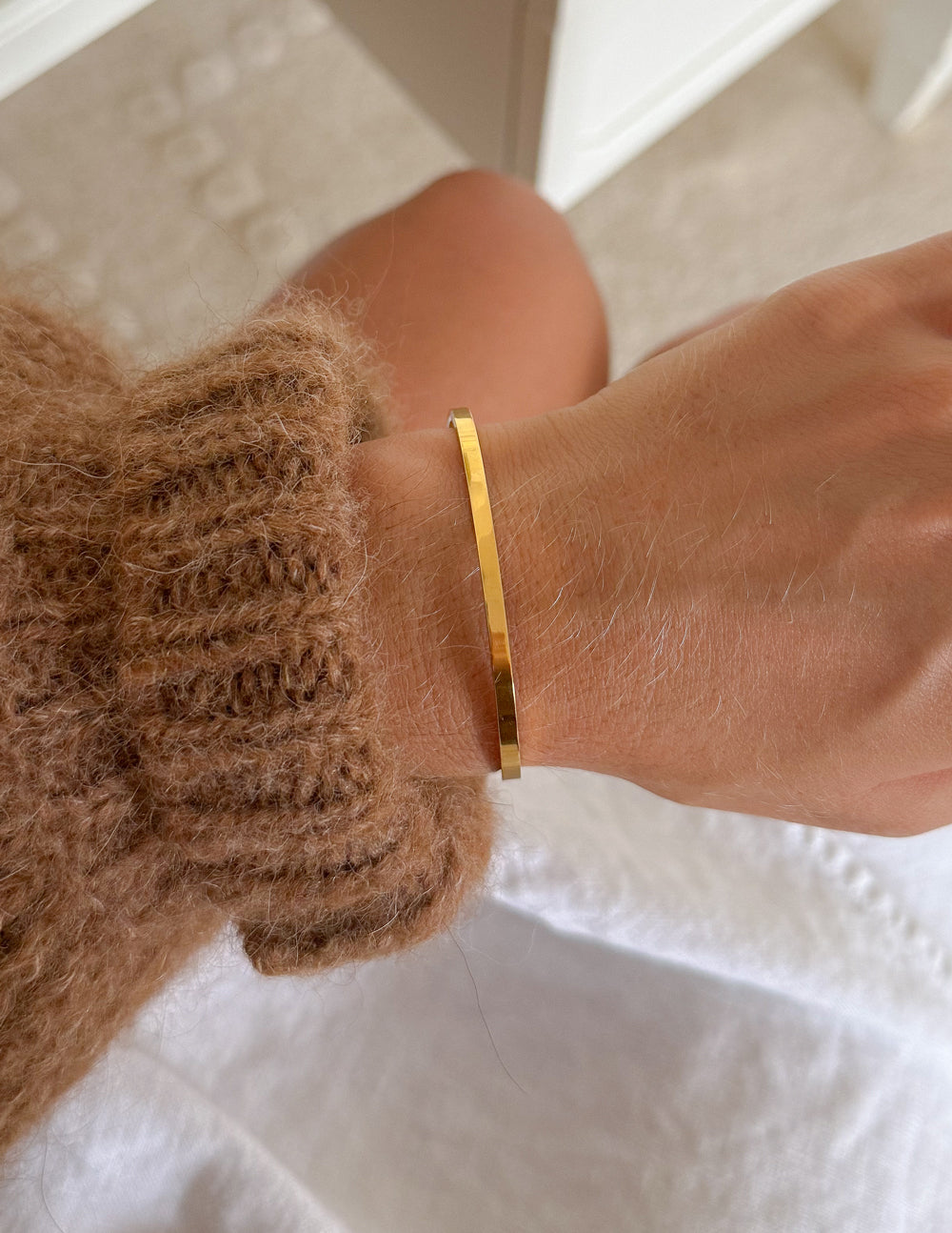 Gold cross cuff bracelet close-up on wrist