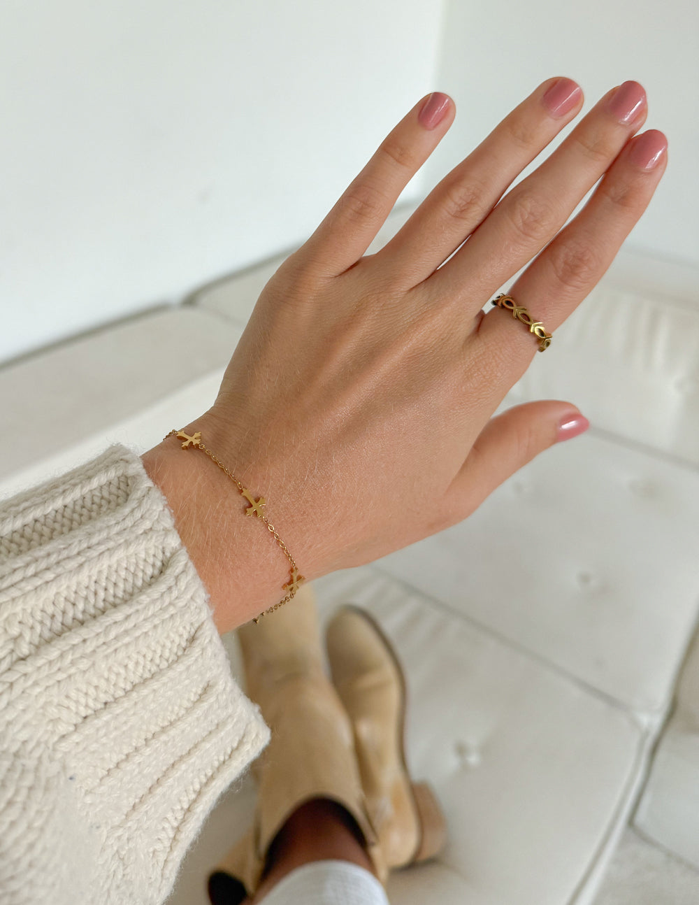 Gold cross link bracelet on hand, chain with cross charms near the wrist.