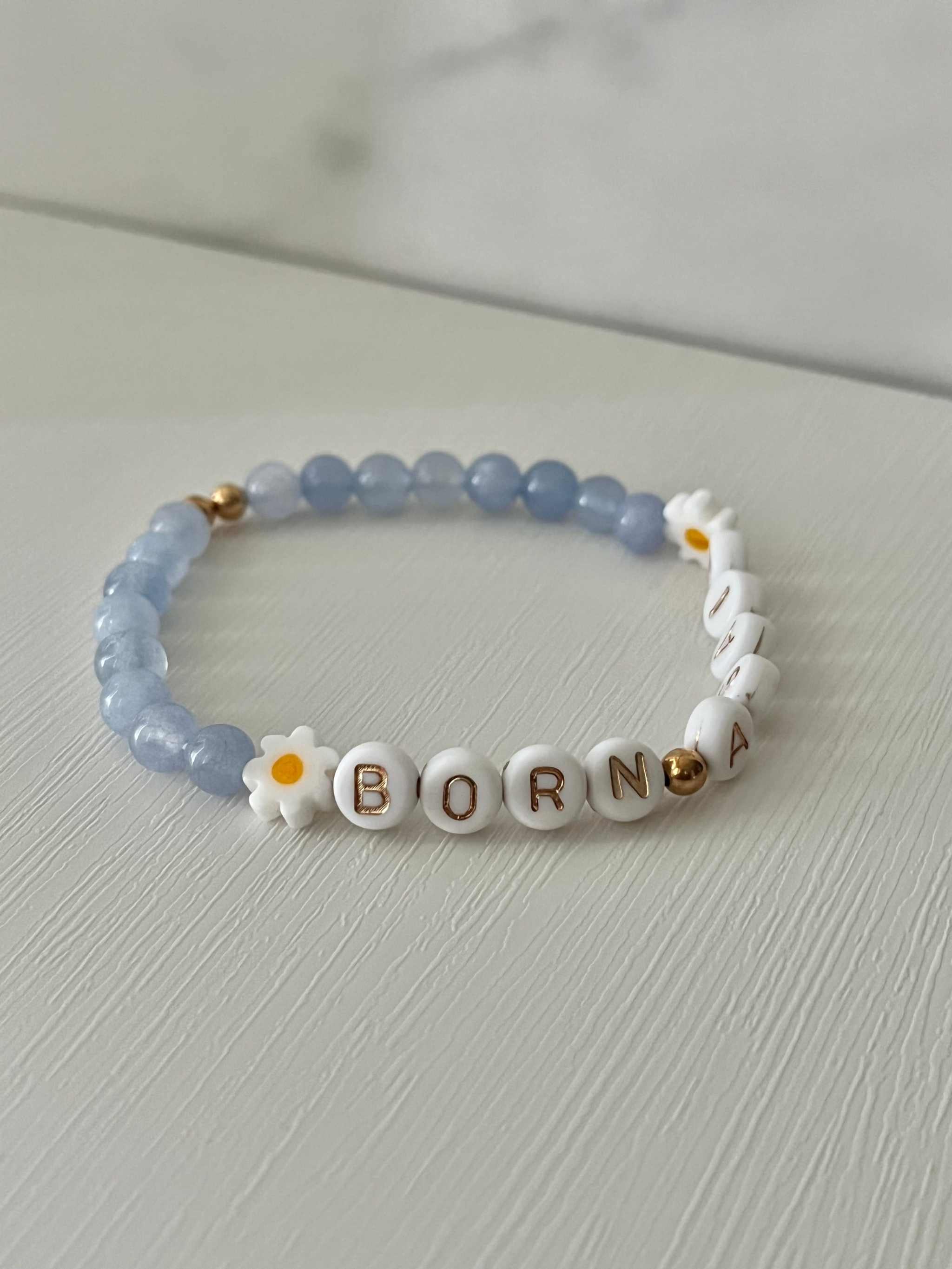 Sky blue beaded bracelet featuring white “BORN AGAIN” letter beads and yellow-white flower charms.