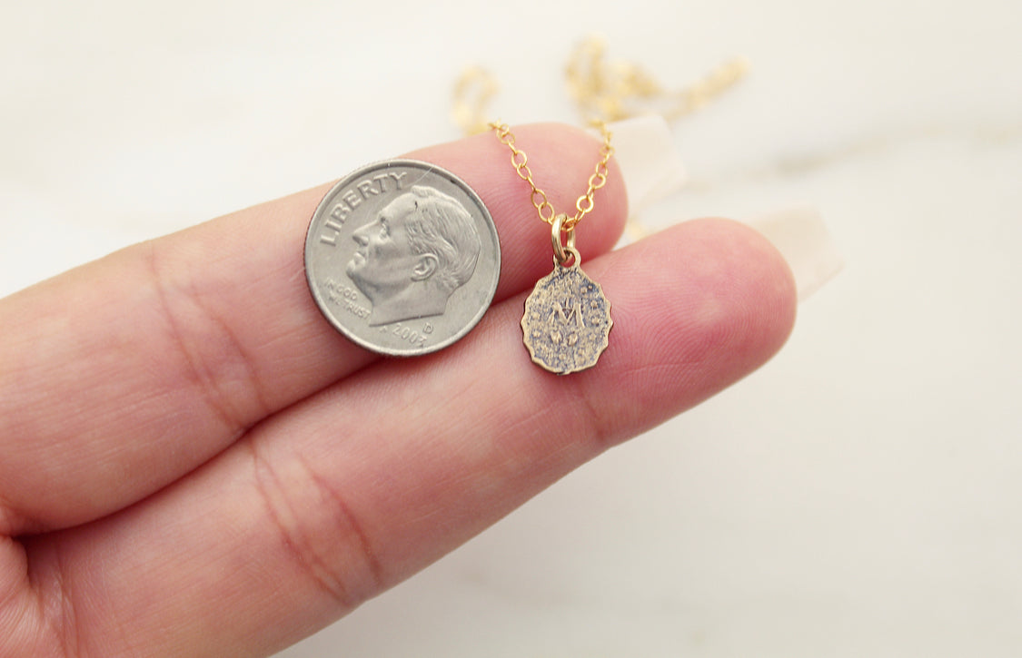Bronze medal pendant on gold chain next to a dime coin for scale.