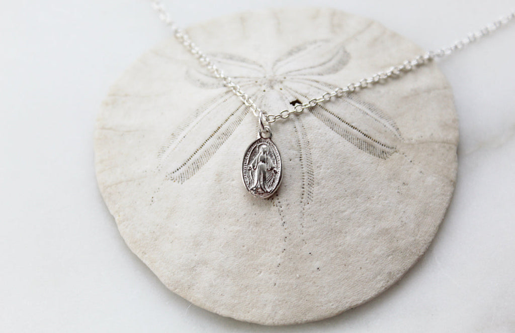 Silver-tone miraculous medal pendant necklace with clasp and oval pendant, flat lay