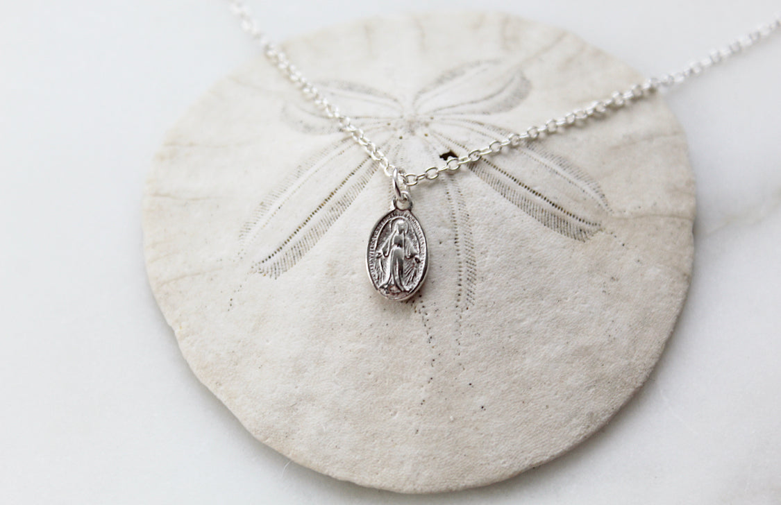 Silver-tone miraculous medal pendant necklace with clasp and oval pendant, flat lay