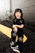 Black kids’ overalls with front straps and white spiderweb patches on legs.