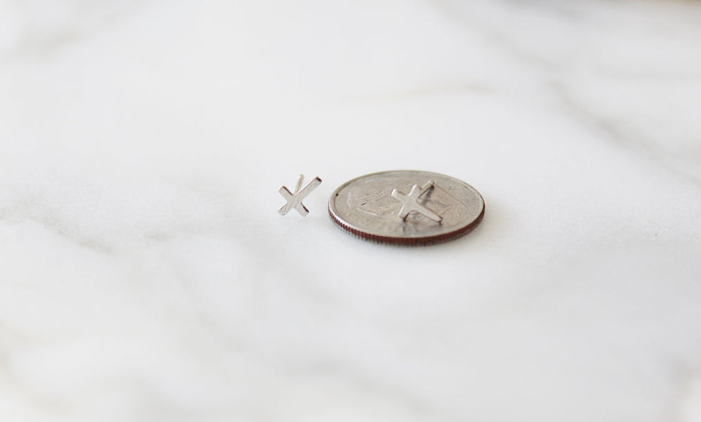 Sterling silver cross stud earrings on a coin for scale, two cross designs visible.
