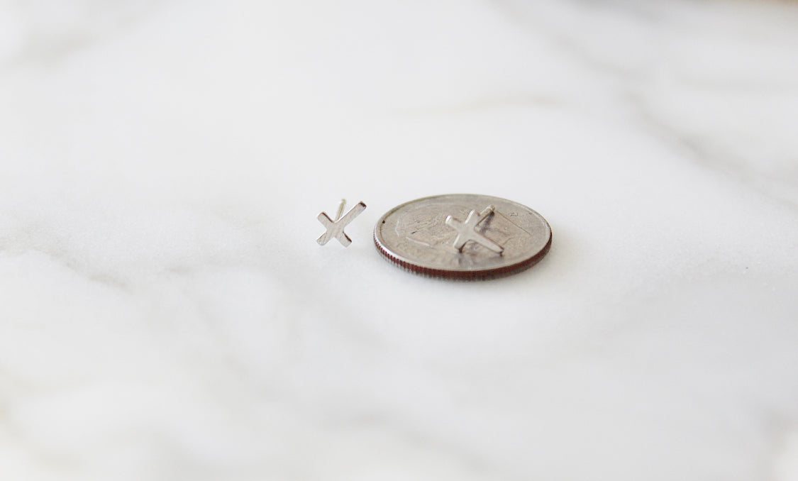 Sterling silver cross stud earrings on a coin for scale, two cross designs visible.