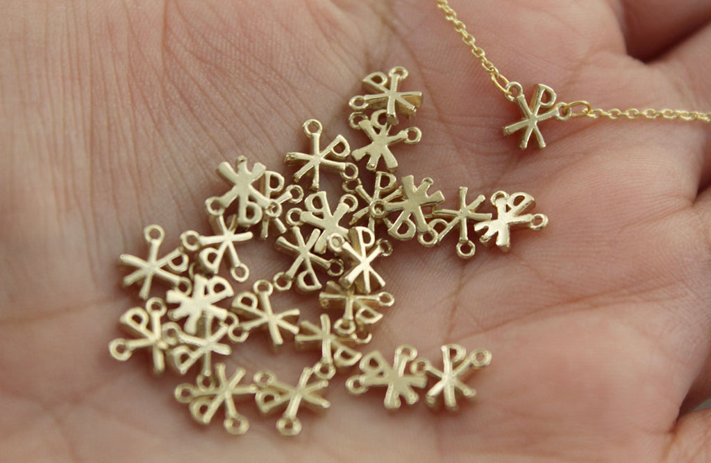 Gold Chi Rho charm pendants spread in an open hand