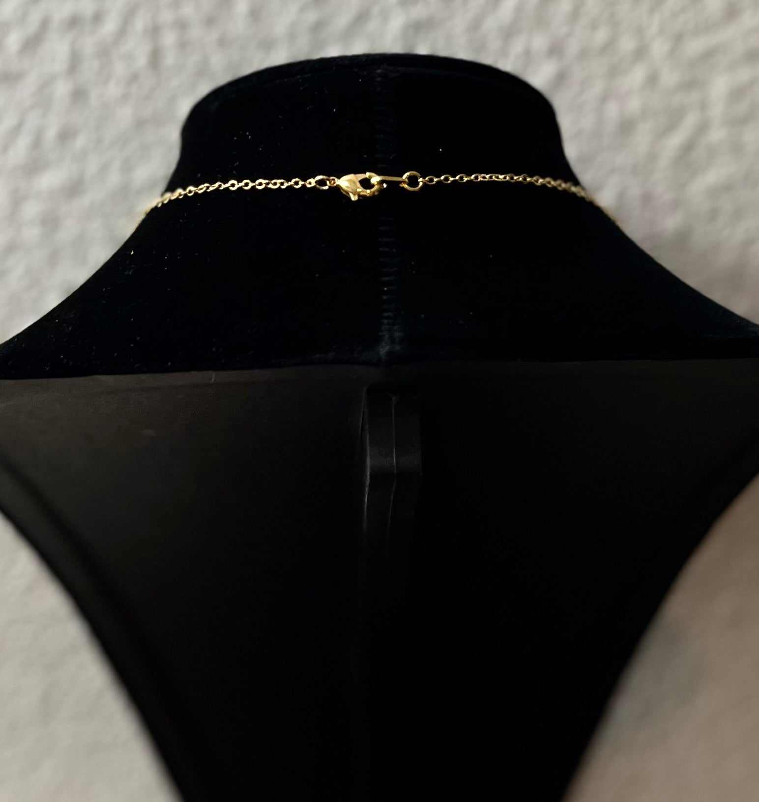 Gold necklace chain with clasp, shown from back on a display bust