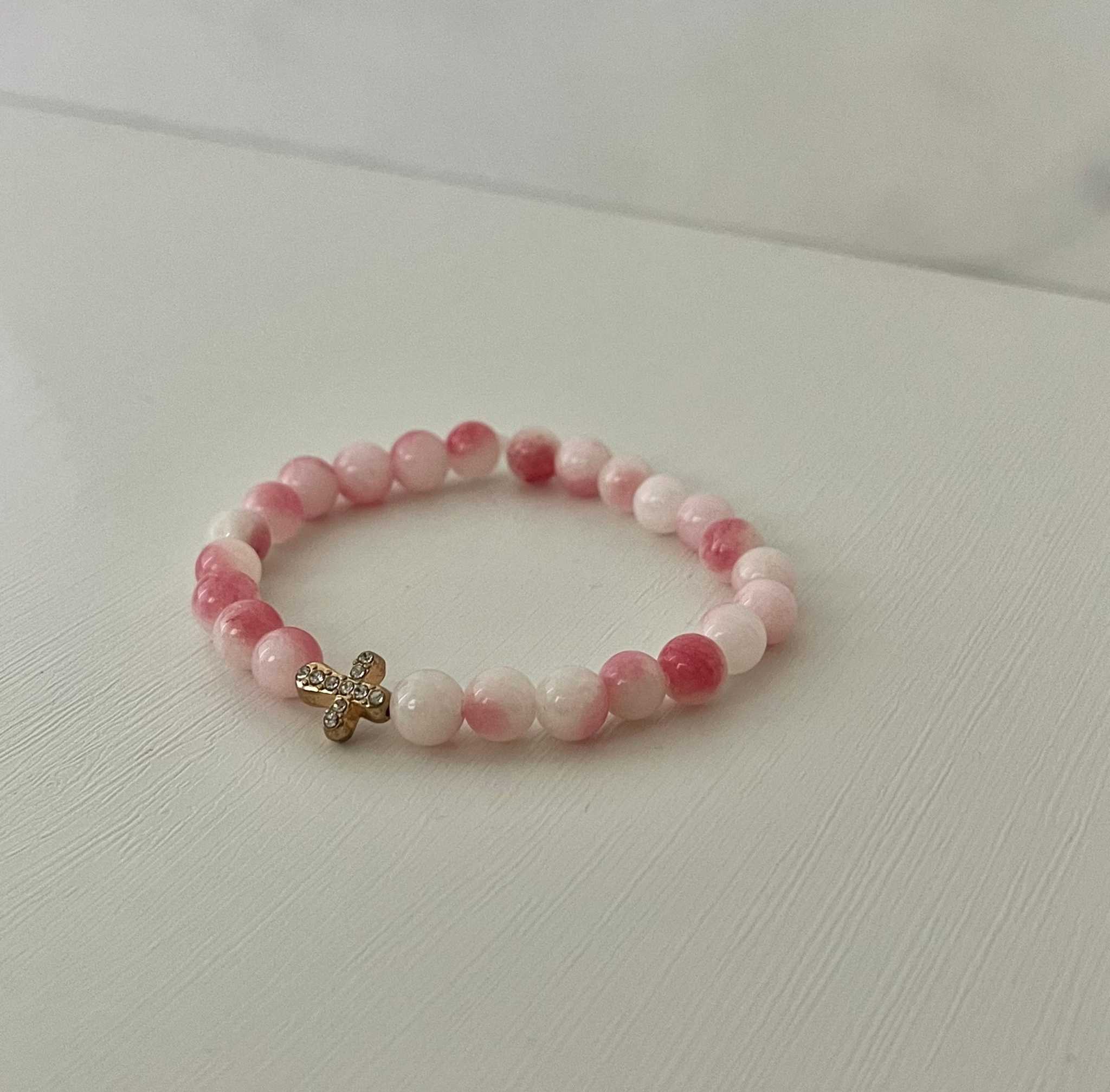 Pink and white bead cross bracelet with small gold cross charm at center.