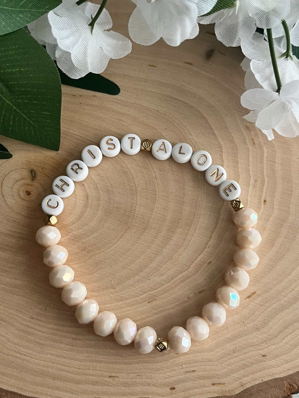 White bead bracelet with round letter beads spelling "CHRIST ALONE" and gold details