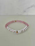 Opal-like iridescent beaded bracelet with pink beads and white letter charms spelling JESUS