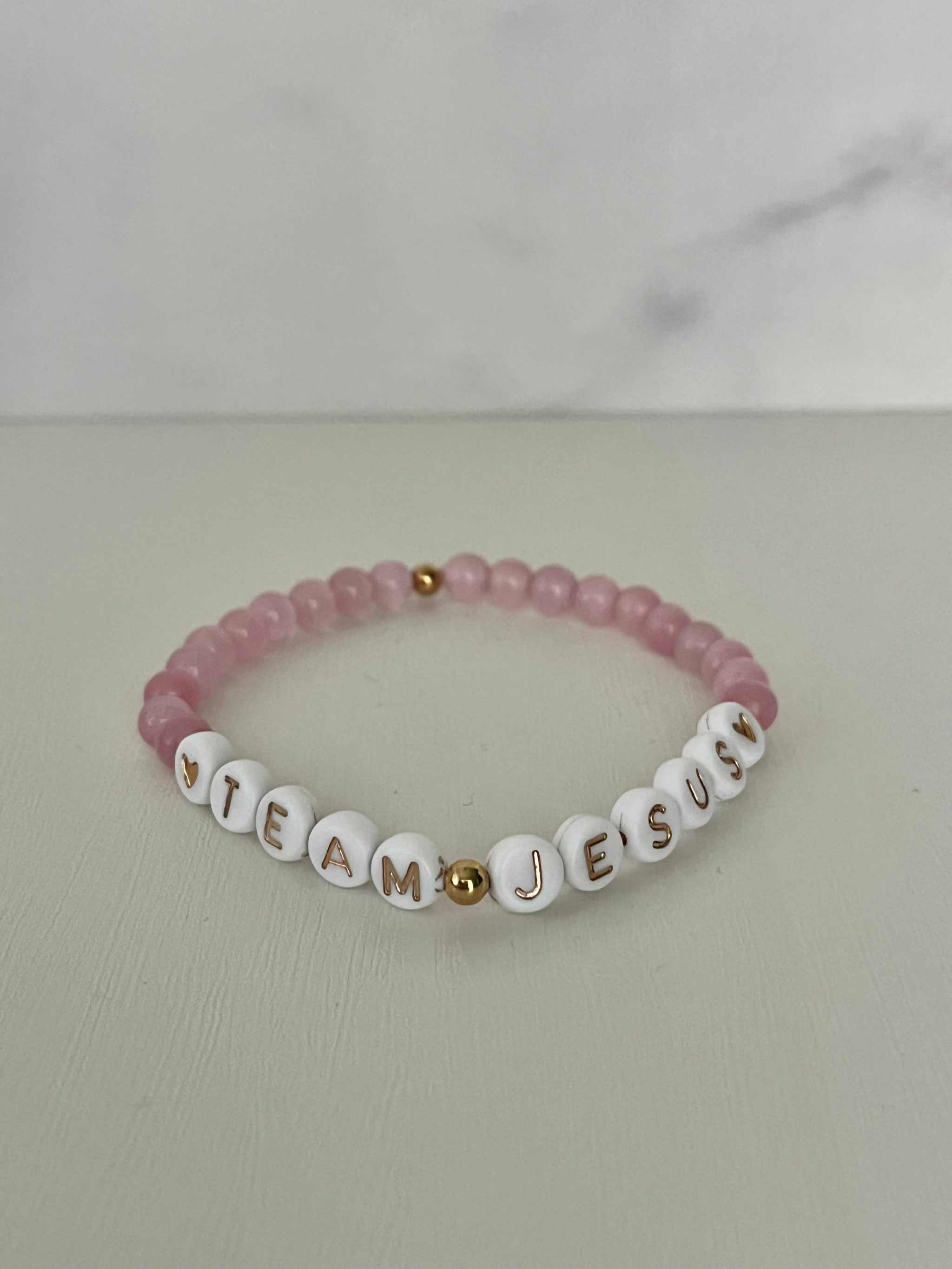 Opal-like iridescent beaded bracelet with pink beads and white letter charms spelling JESUS