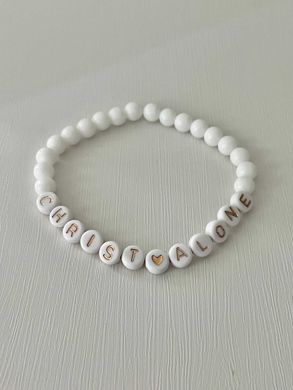 White bead bracelet with “Christ Alone” letter beads and heart accent