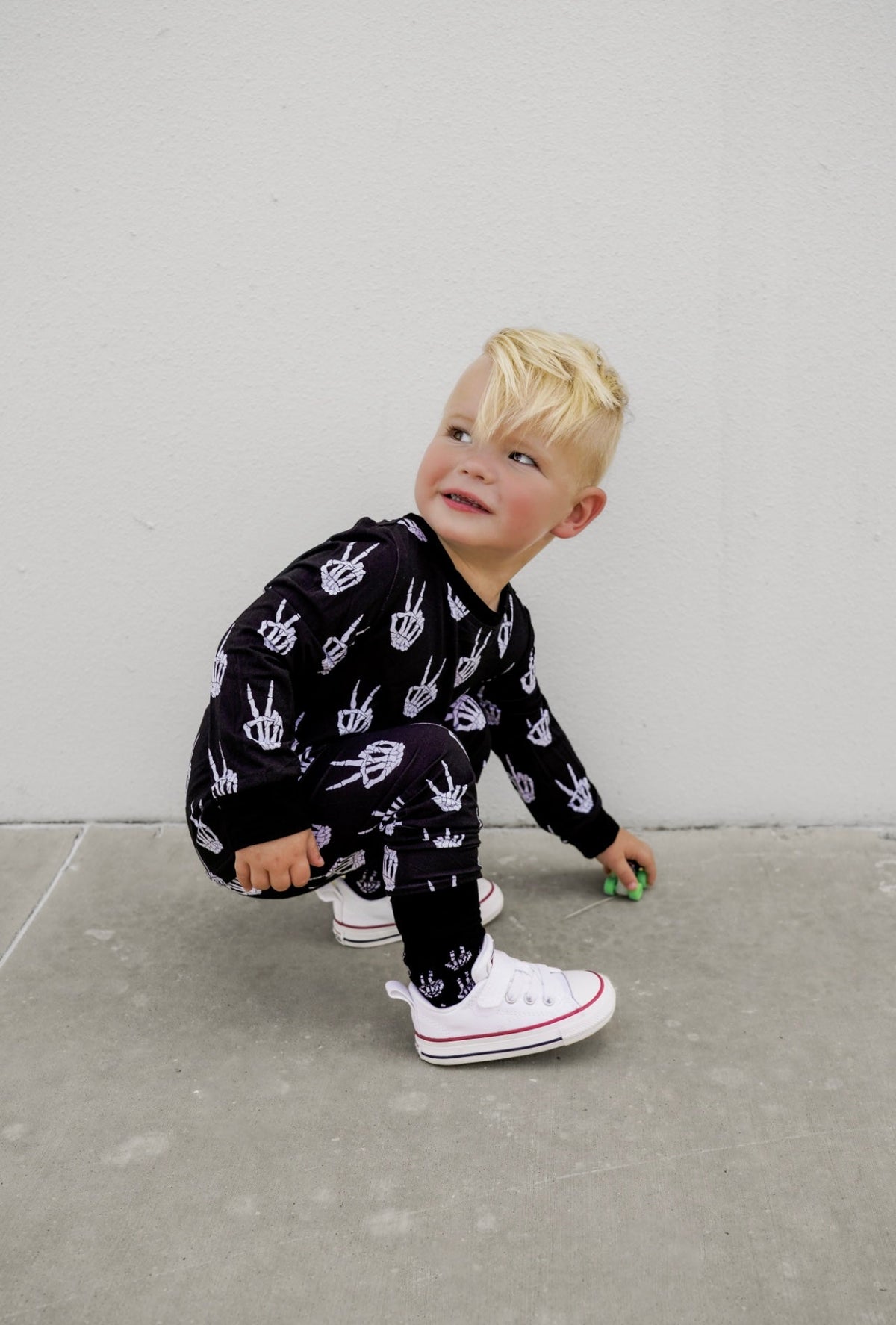 Kids black long-sleeve pajama set with white skeleton-hand print, tapered cuffs.
