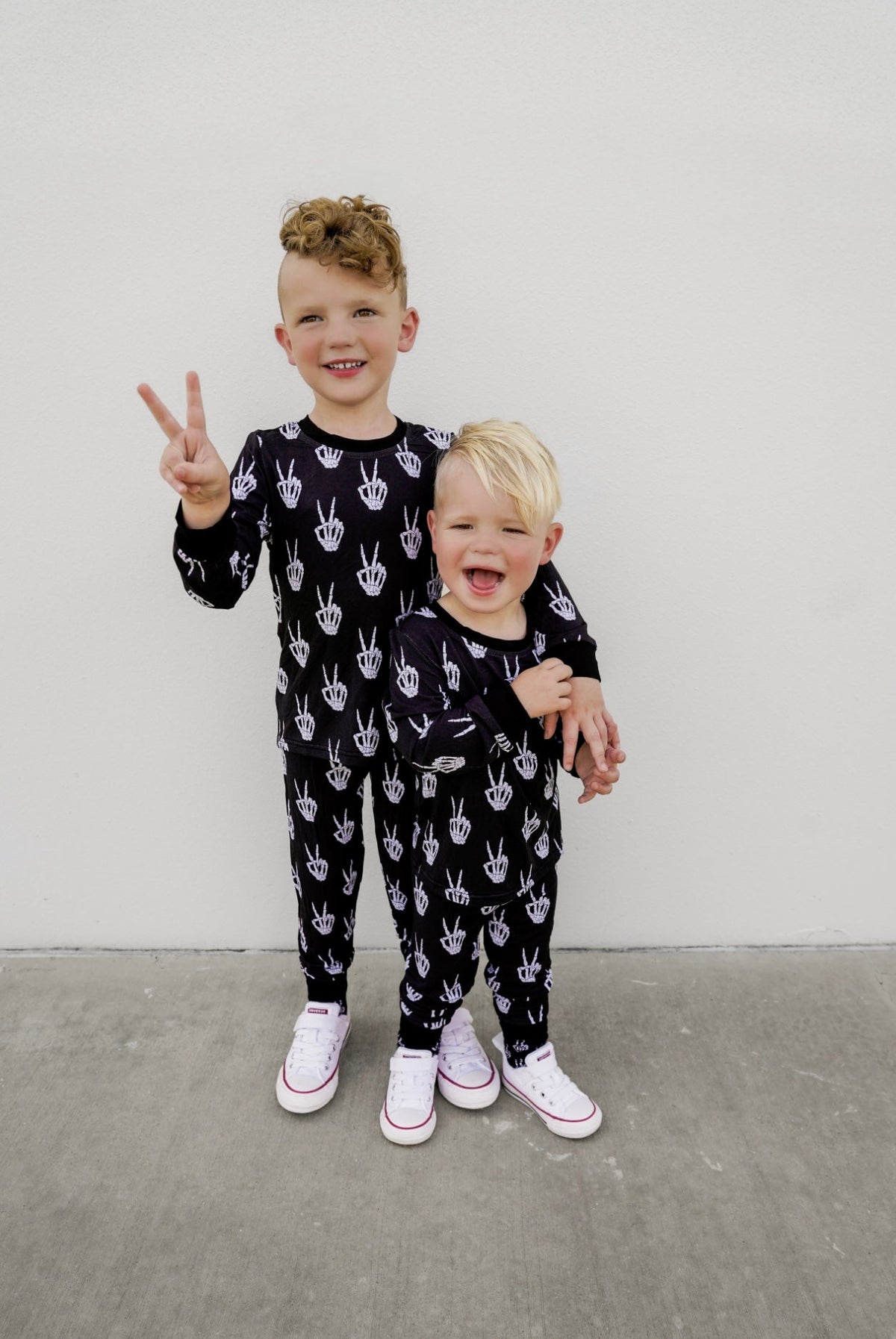 Kids black long-sleeve pajama set with repeating white skeleton-hand print.