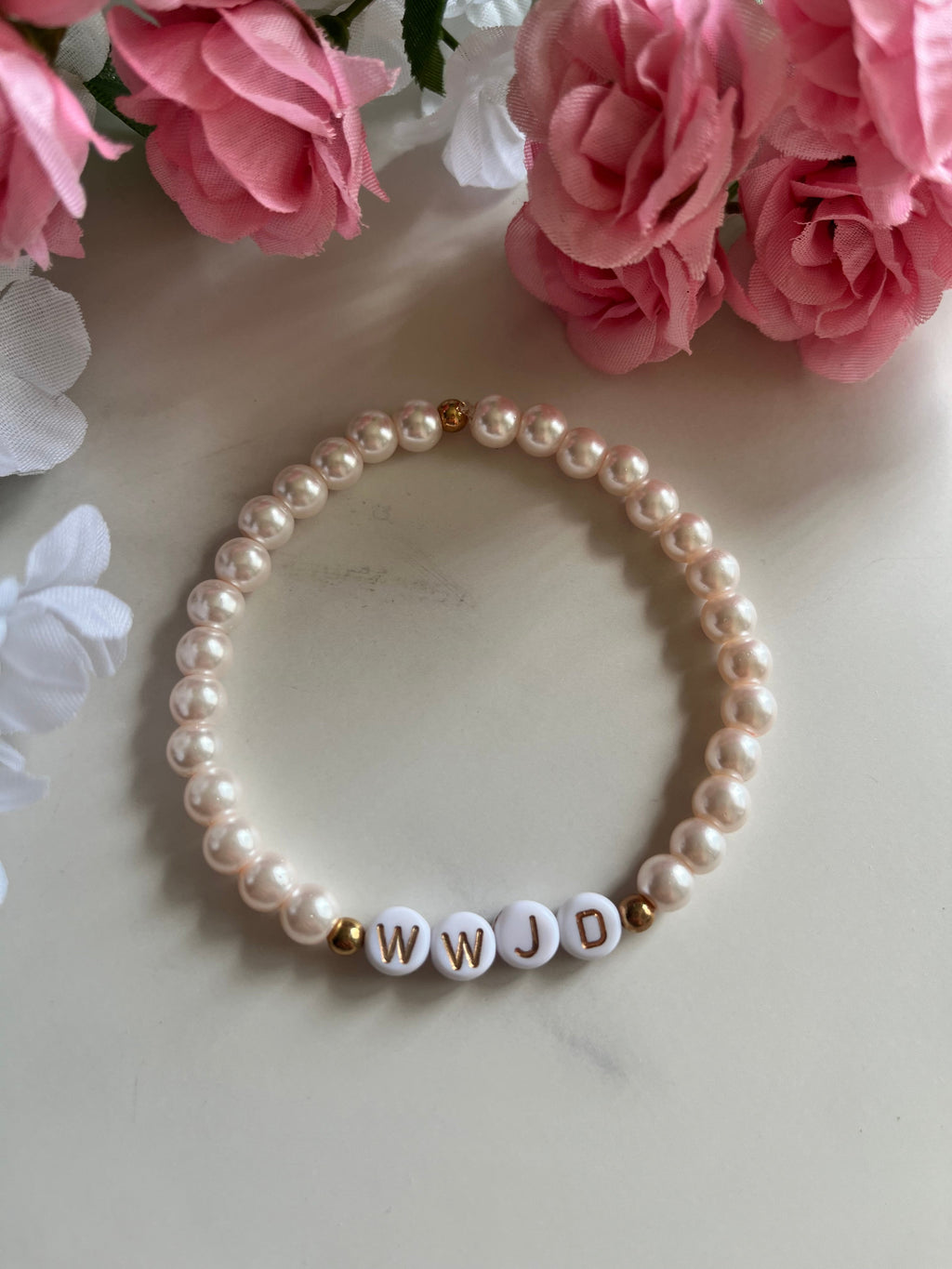 Pearl bead bracelet with WWJD letter beads in gold on a strand of white round pearls.