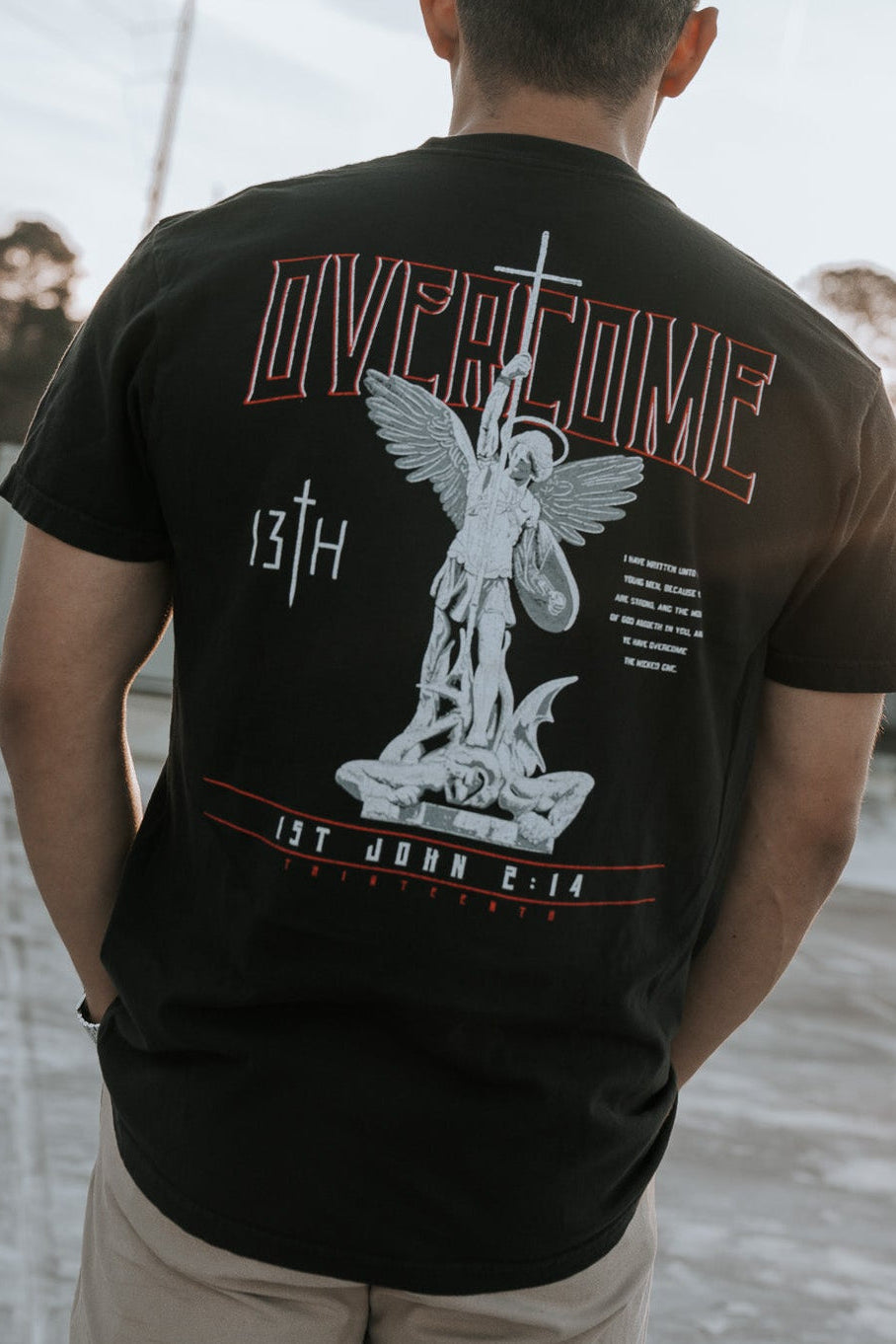 Black tee shirt with large back Overcome angel graphic and red banner text