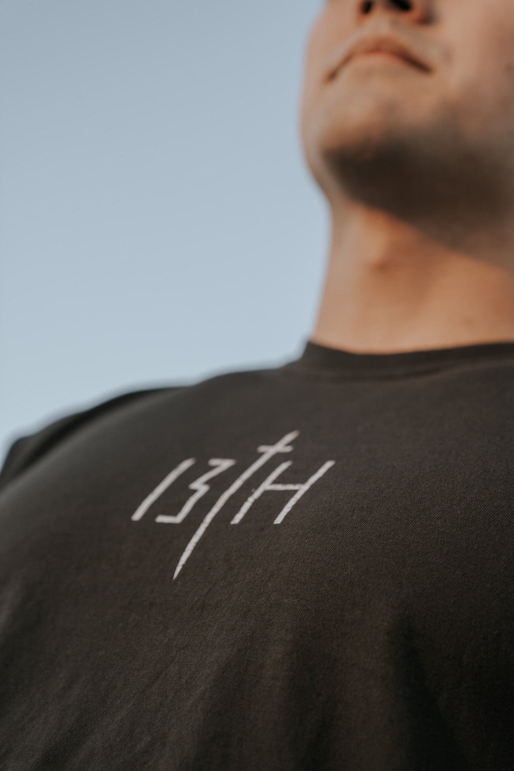 Black tee shirt close-up front with white cross and '13TH' mark