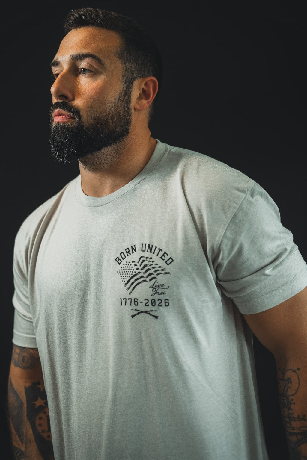Light gray front T-shirt with small “Born United” anniversary emblem and star accents