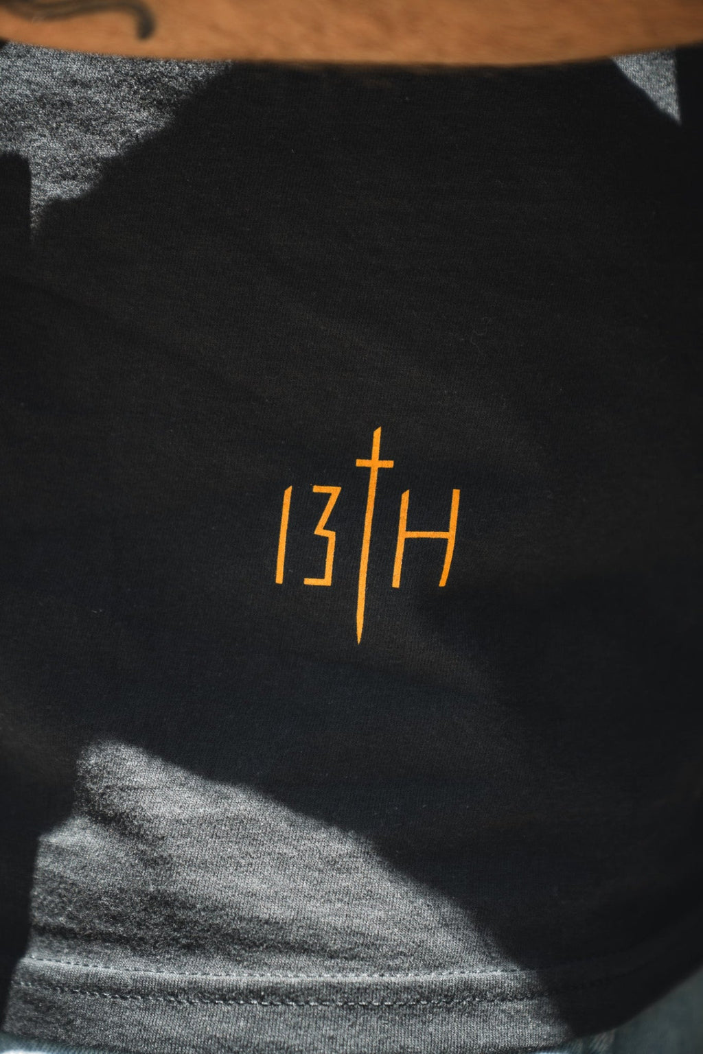 Black premium tee close-up showing orange "13th" print