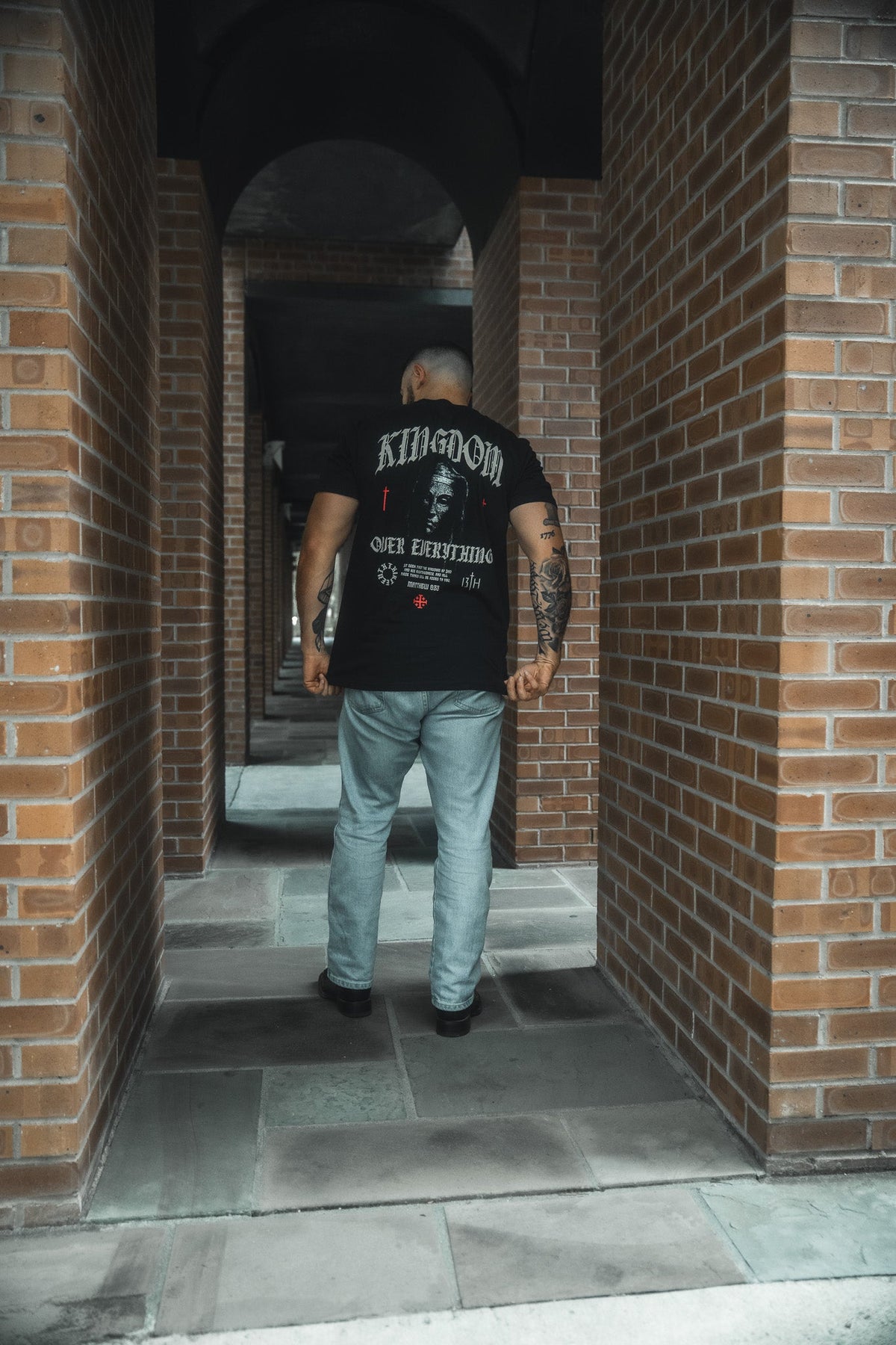 Black crew-neck tee with back graphic print, model standing in corridor