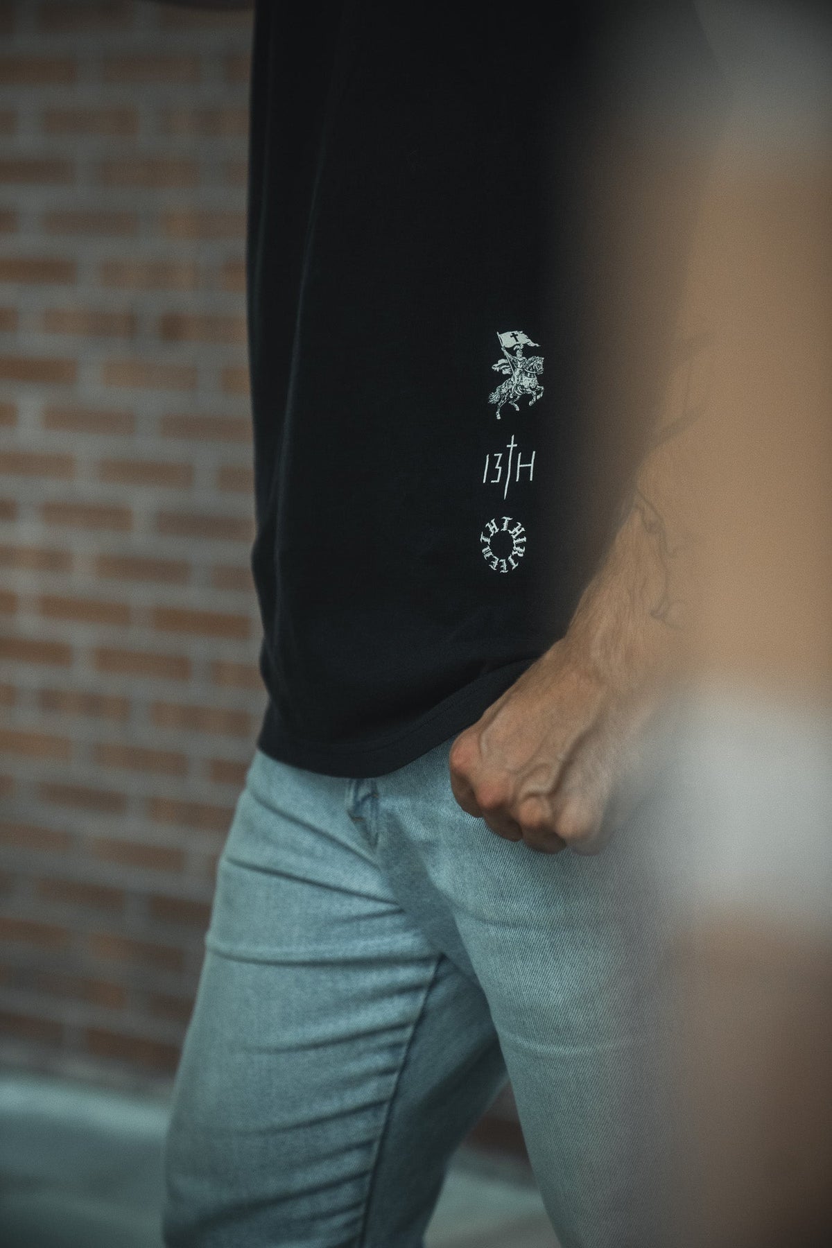 Black tee with small white emblem and '13TH' text on back