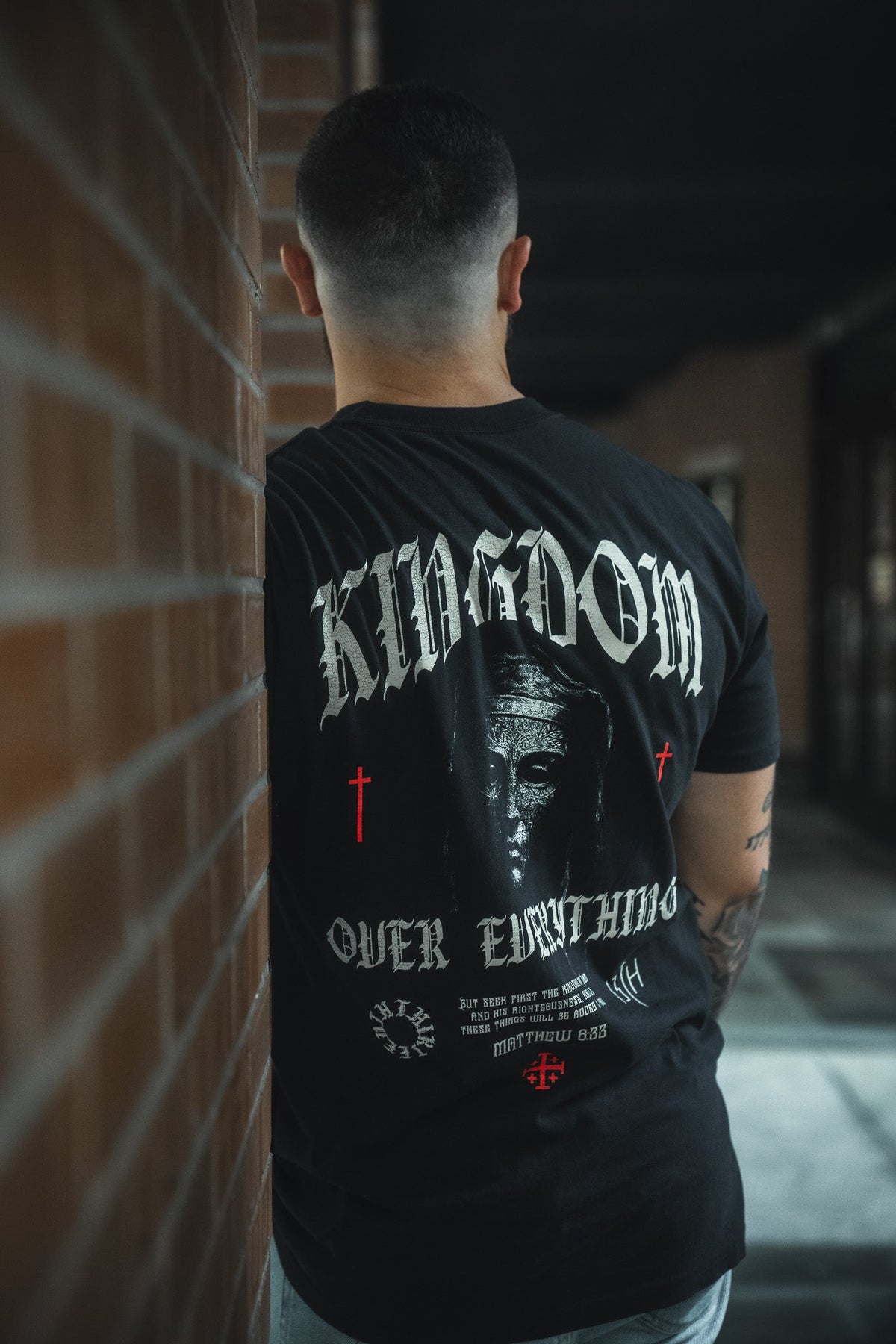 Black premium graphic tee back view with central portrait and cross accents print.