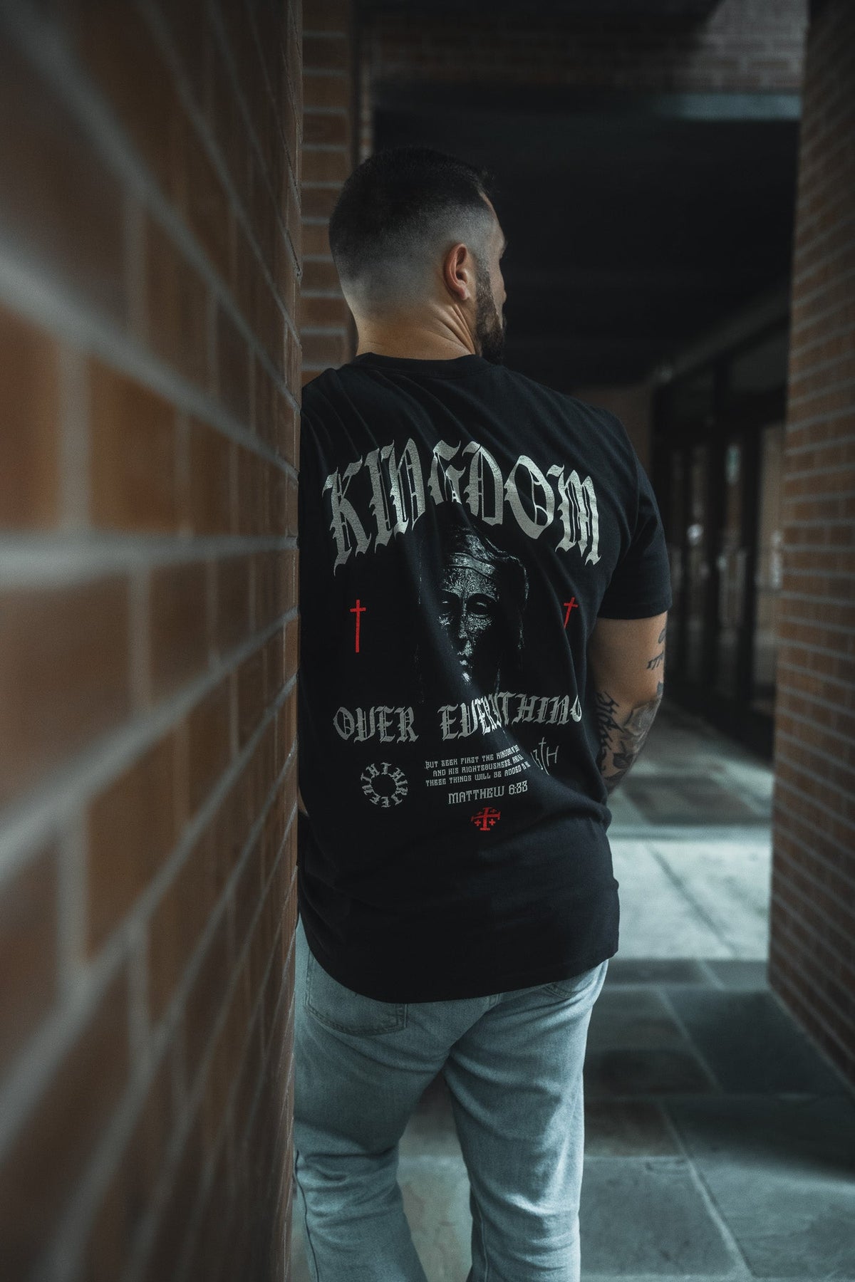 Black premium graphic tee back view with full-size artwork and text print, crew neck.
