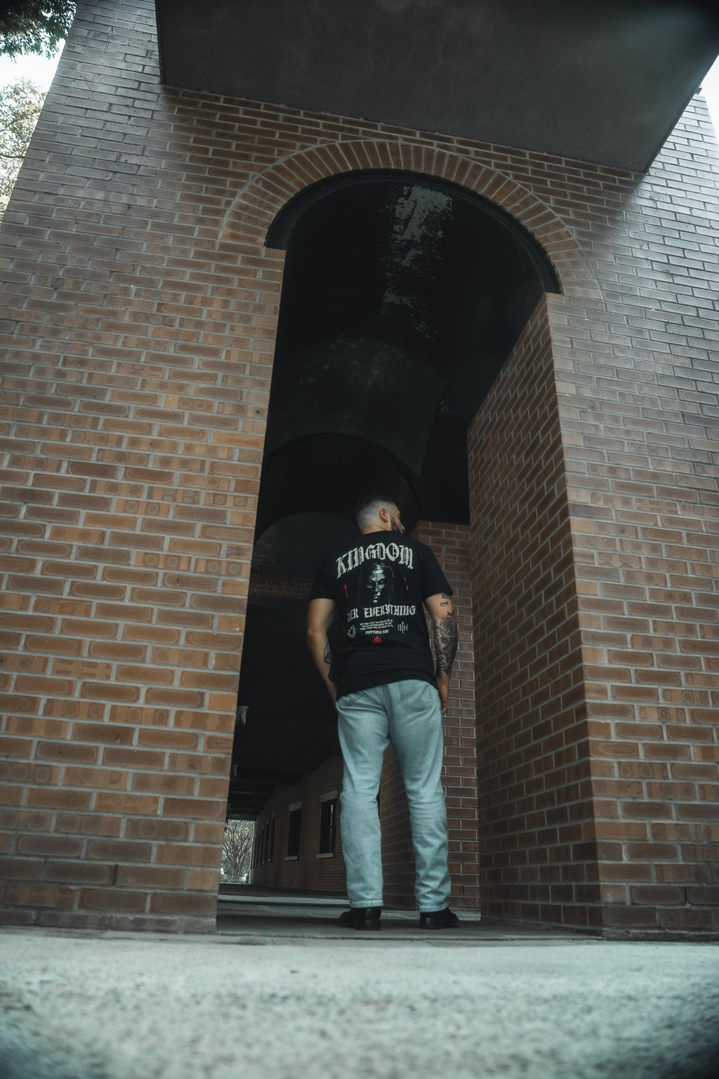 Black premium graphic tee worn outdoors, front logo centered on chest.