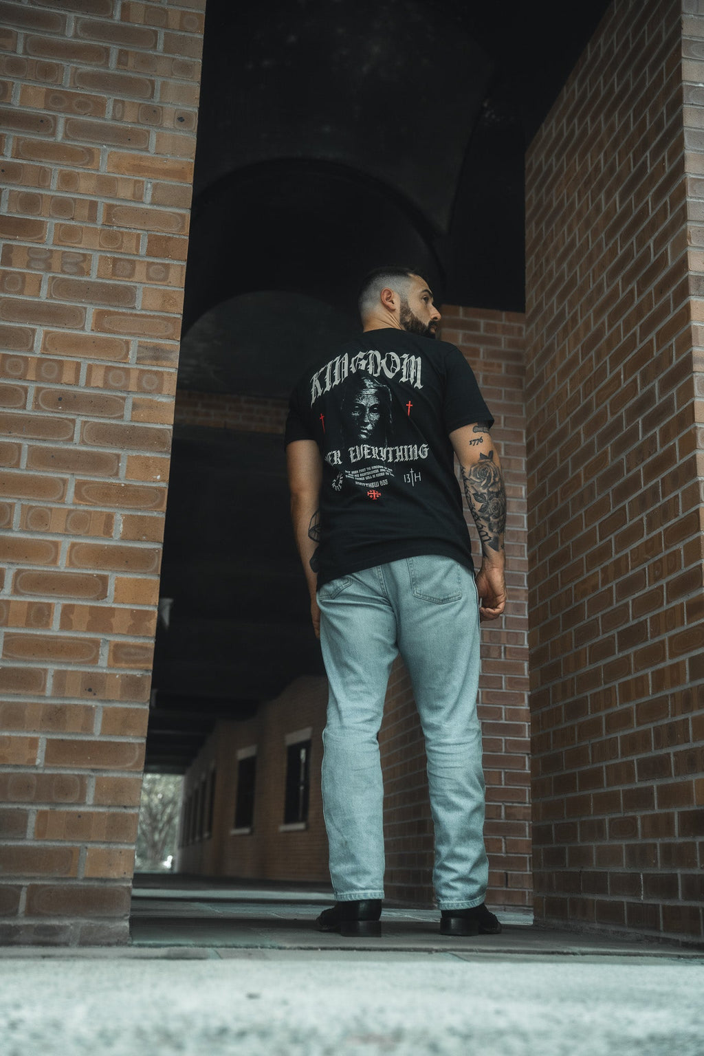 Black premium graphic tee back view, large banner portrait artwork print visible.