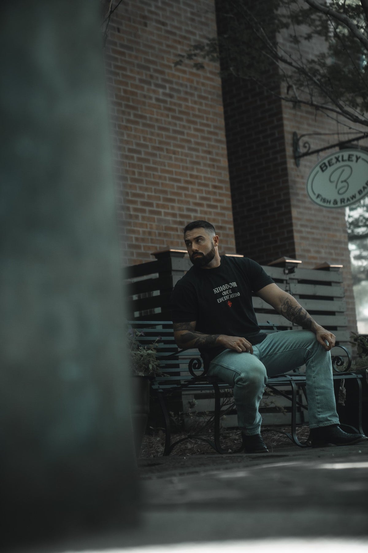 Black premium graphic tee front view with small logo and text print, crew neck.