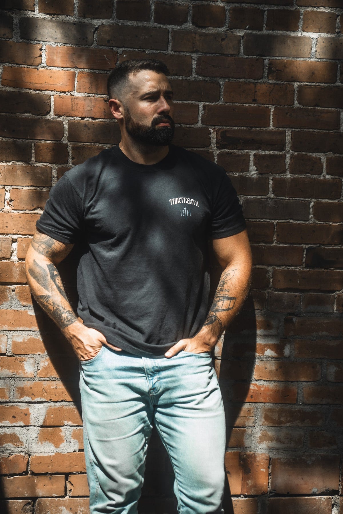 Black crewneck T-shirt with small white THIRTEENTH and 13TH logo on model