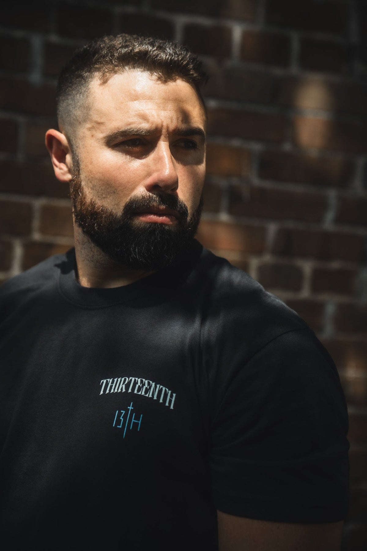 Black crewneck T-shirt with small white THIRTEENTH 13TH chest print on model