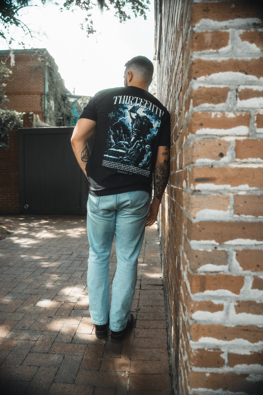 Black premium T-shirt with large blue THIRTEENTH back graphic on standing model