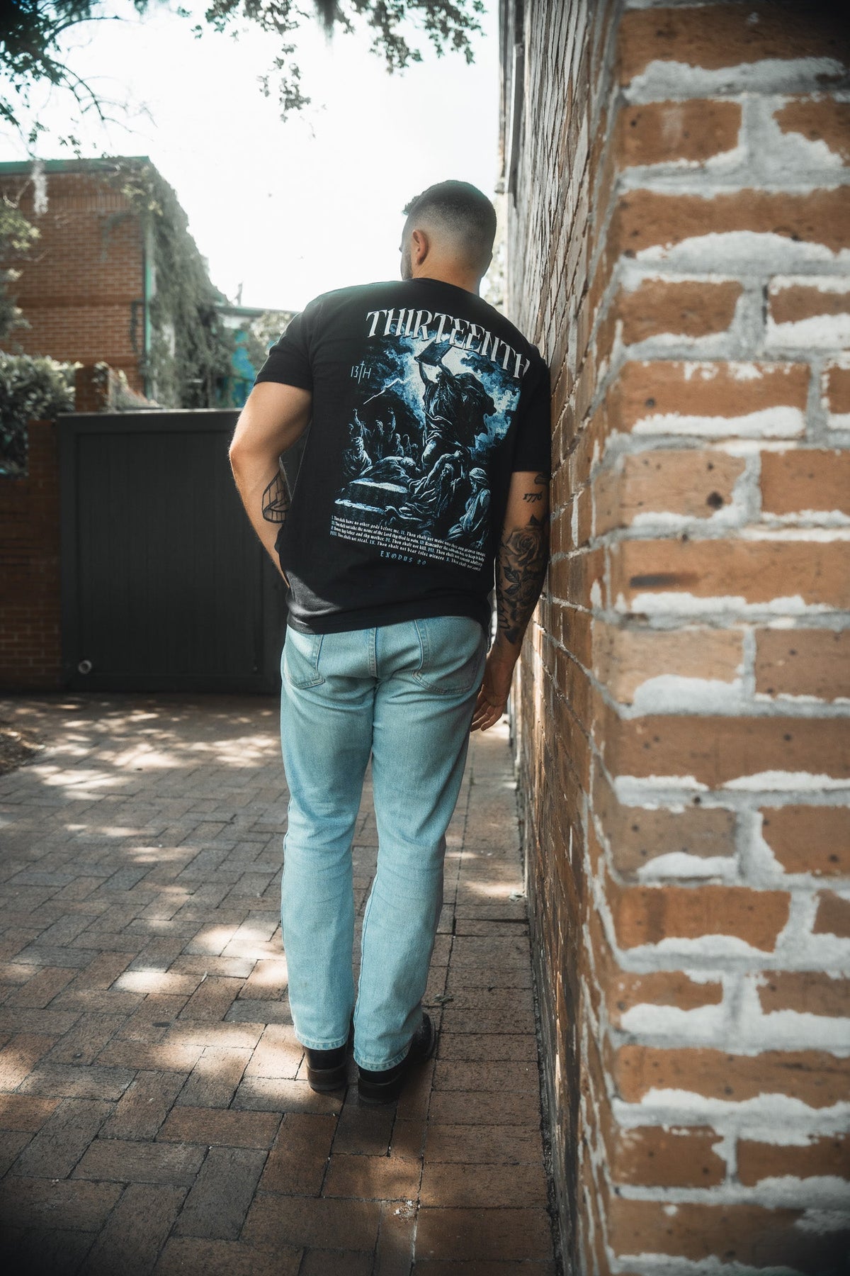 Black premium T-shirt with large blue THIRTEENTH back graphic on standing model