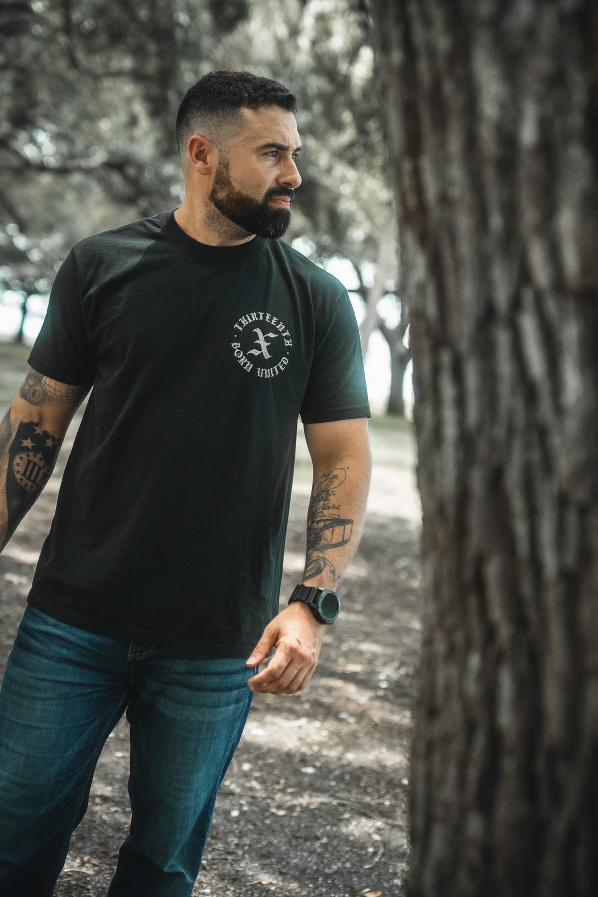 Black T-shirt with circular chest emblem, crew neck, and short sleeves.