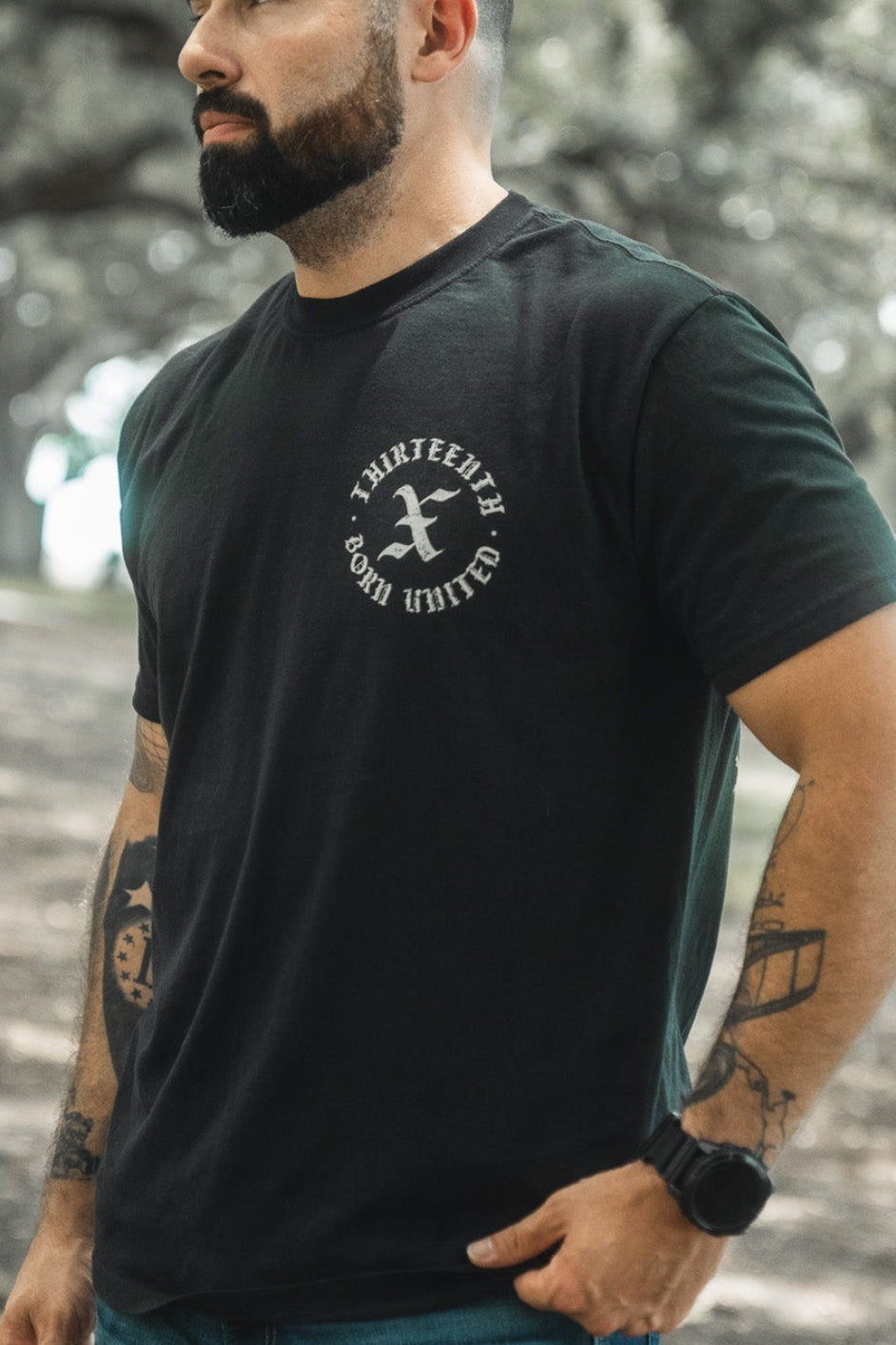 Black T-shirt with small circular chest emblem and crew neck.