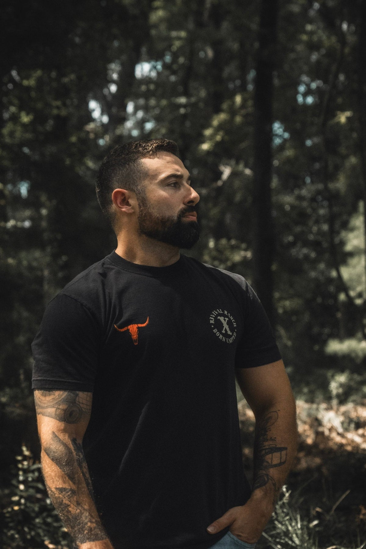 Black tee with small orange bull logo and circular emblem on chest