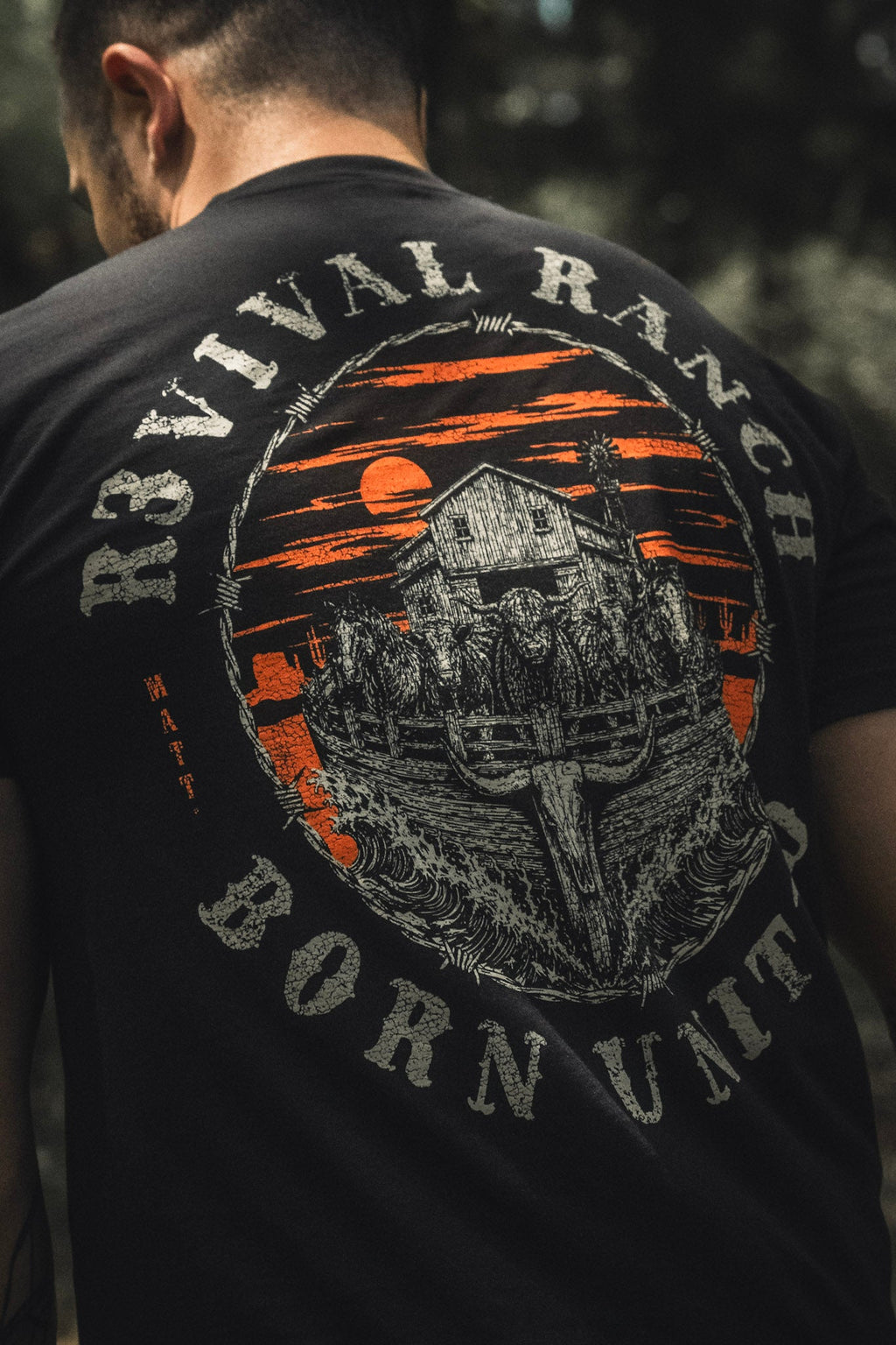 Black tee back print close-up, gray farm illustration in orange arch emblem