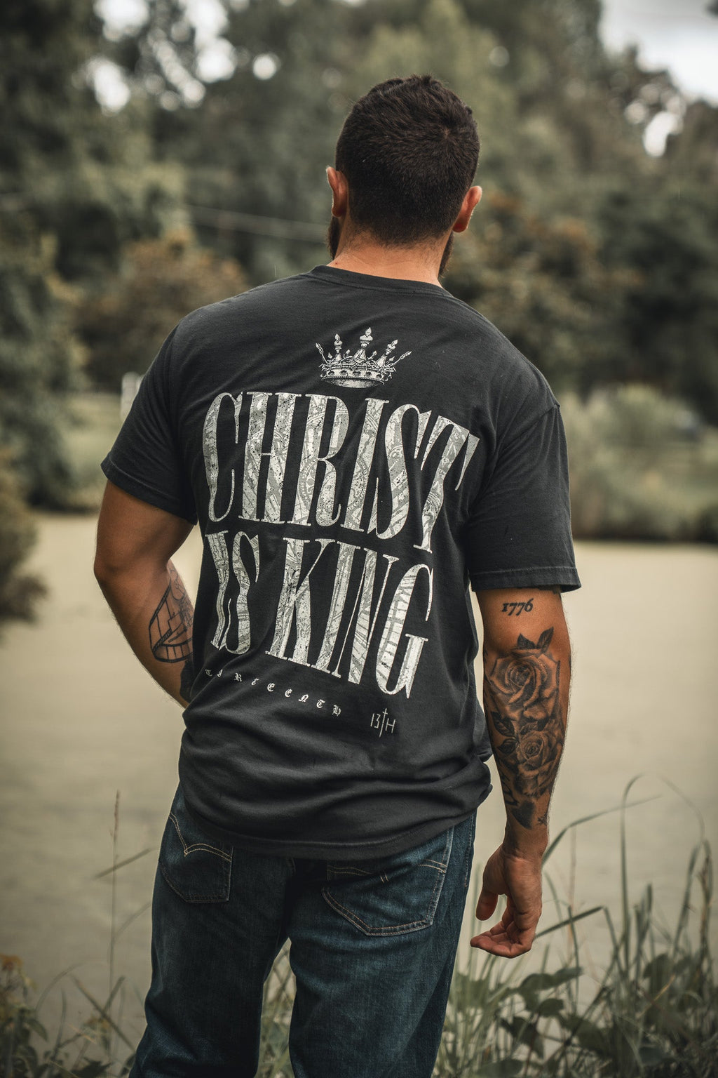 Black T-shirt back view with "CHRIST IS KING" typography and crown