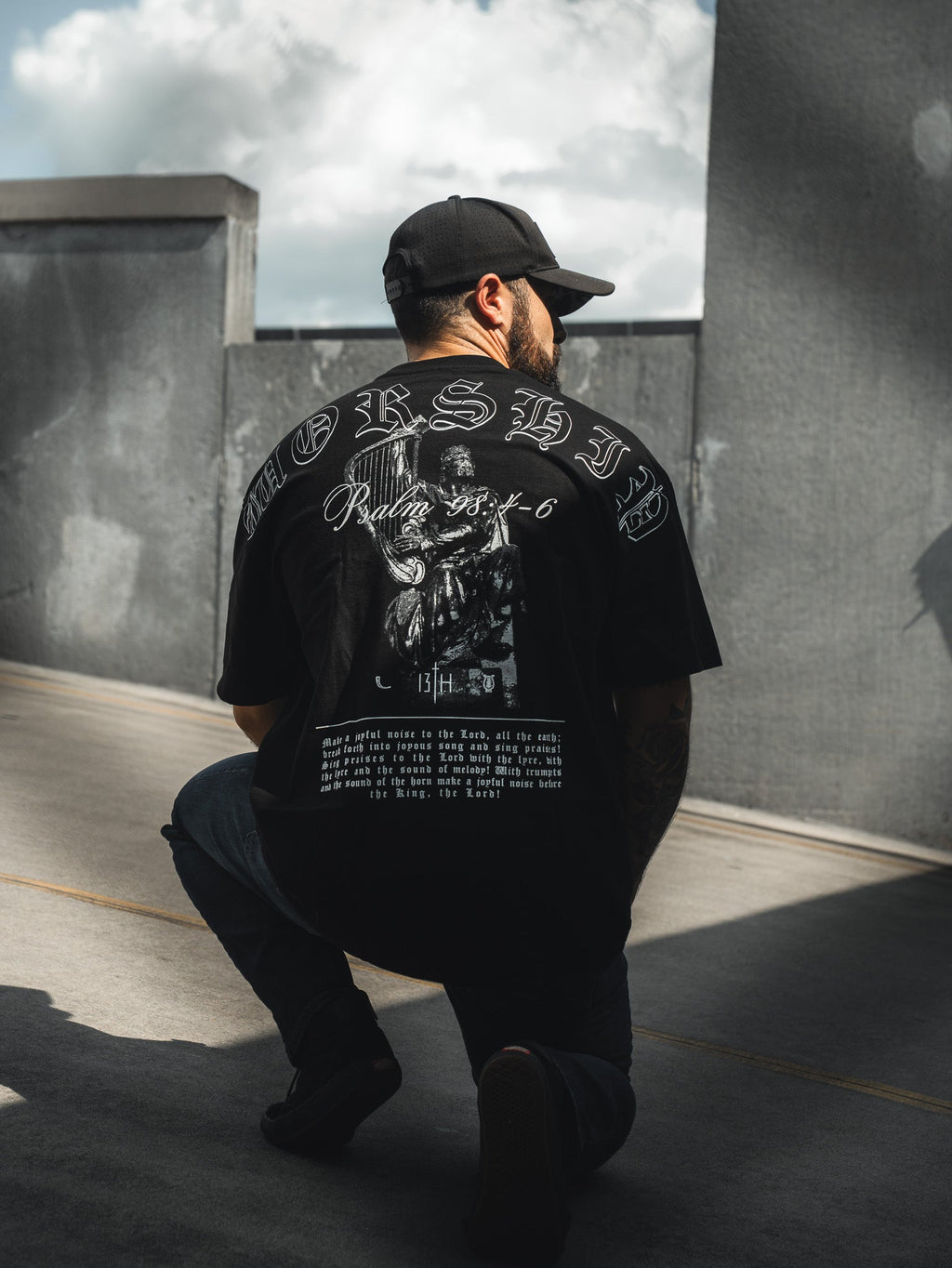 Black oversized tee with back print featuring ornate text and portrait in white.