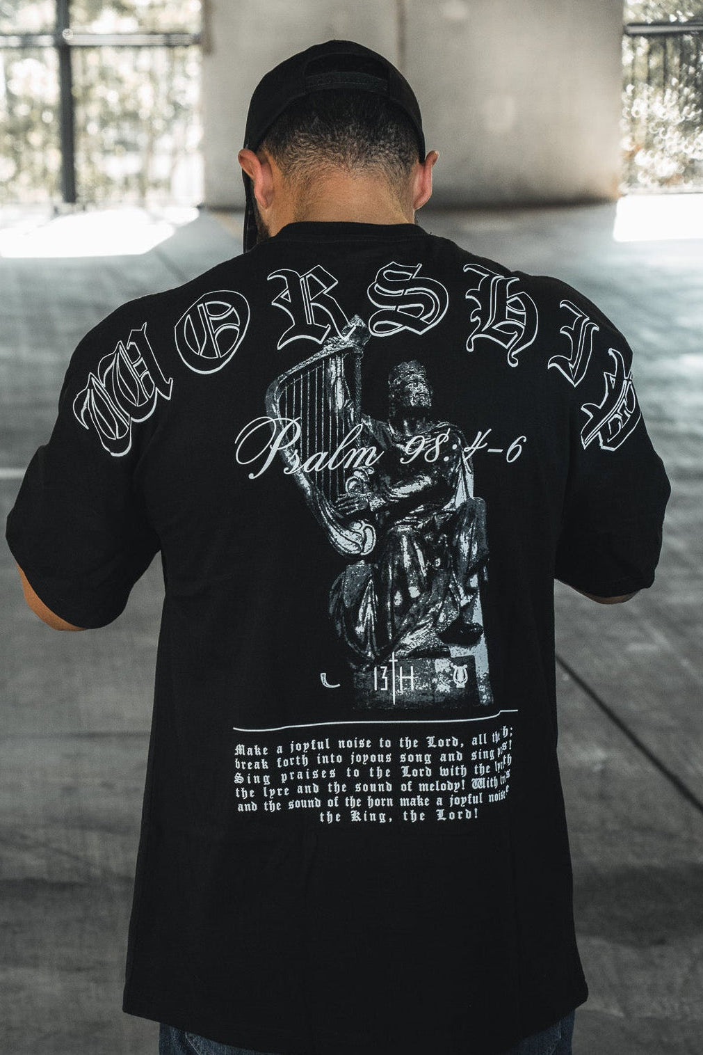 Black oversized tee with large back graphic and ornate white-and-gray lettering.