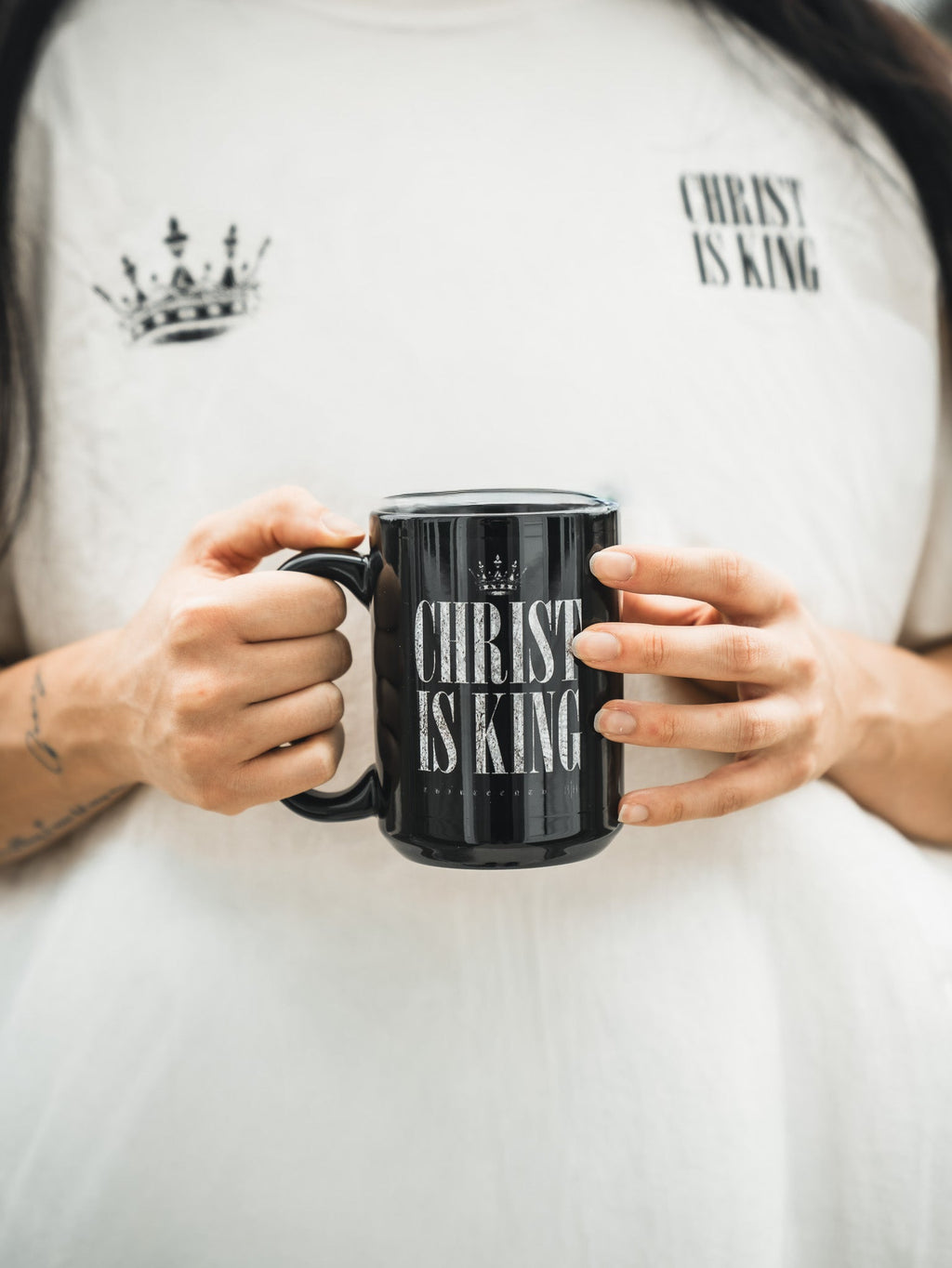 Black mug held in hands with CHRIST IS KING design on the front