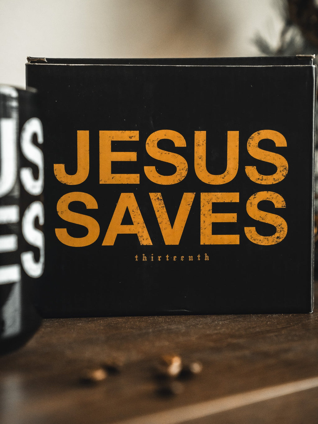Black gift box with orange 'JESUS SAVES' text and 'thirteenth' on front