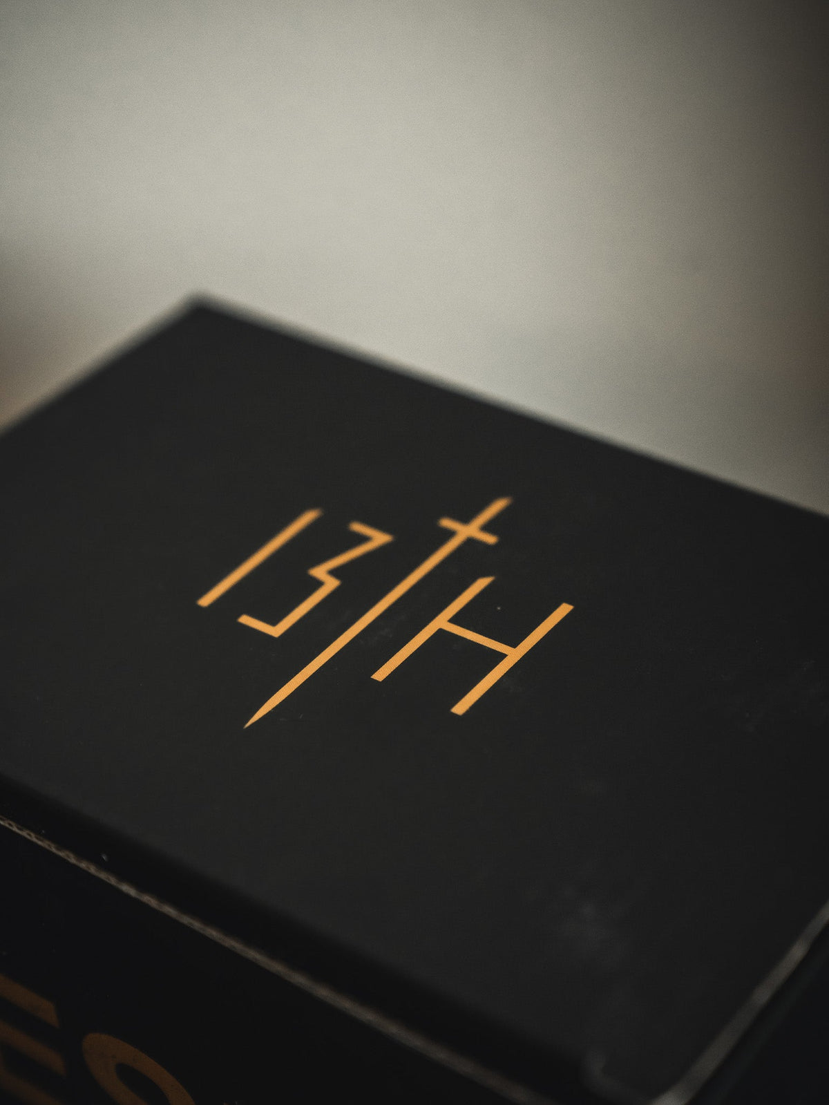 Black gift box lid with gold 'JH' cross-like lightning symbol design