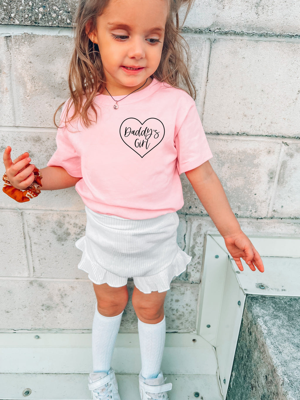Pink baby T-shirt with 'Daddy's Girl' heart logo, worn by child