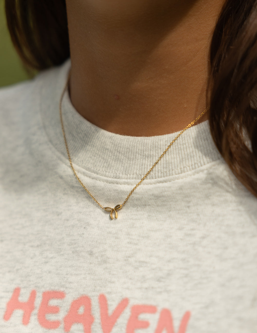 Gold bow pendant necklace with fine chain and small bow charm at center